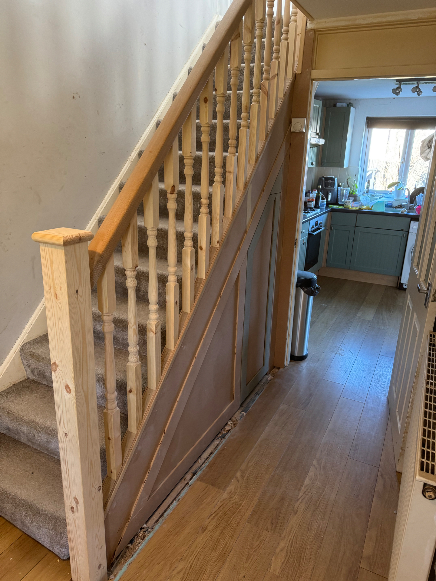 Newly fitted pine staircase with turned spindles and understairs panelling before finishing
