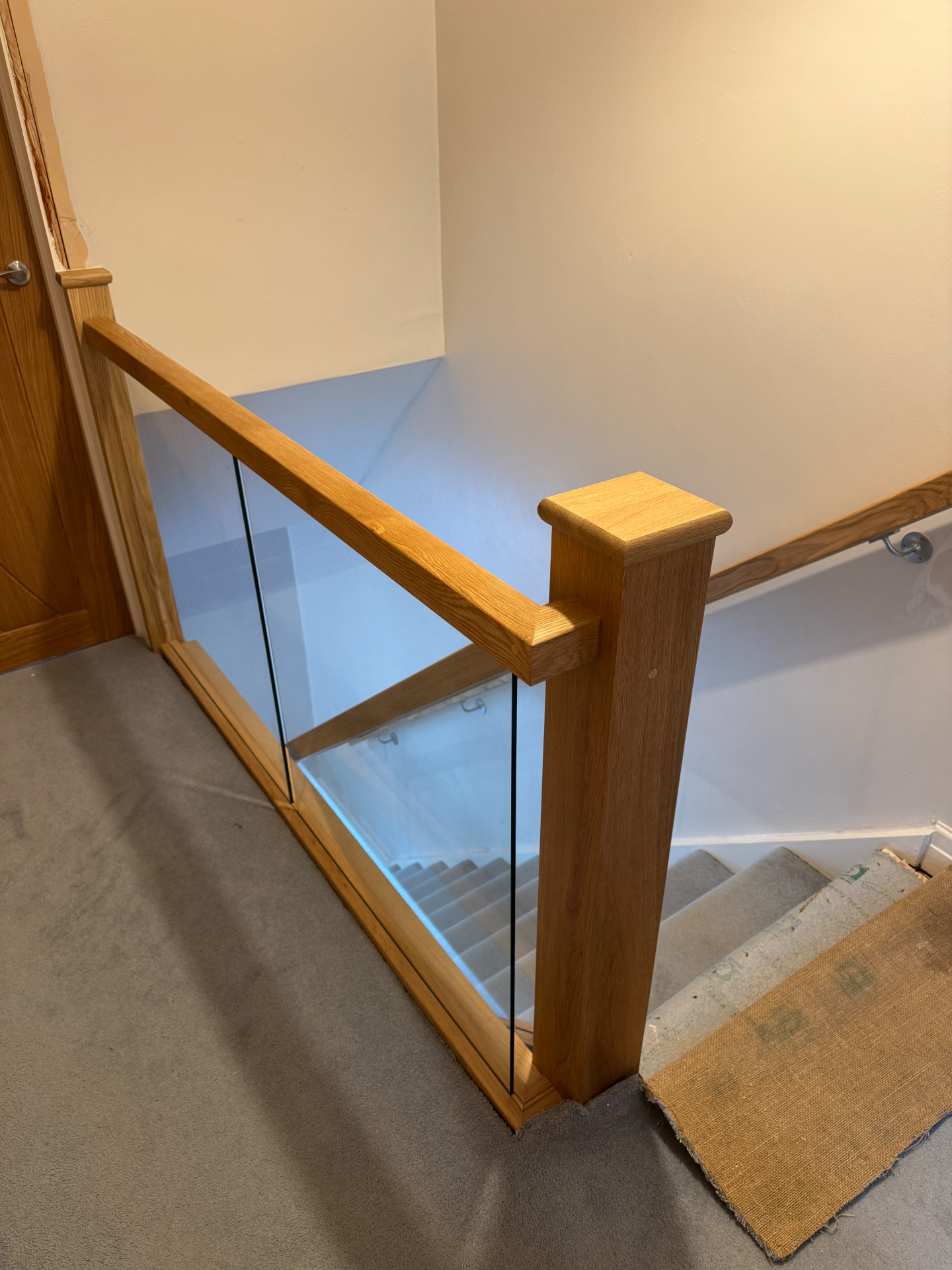 Close-up of an oak newel post and glass balustrade joint