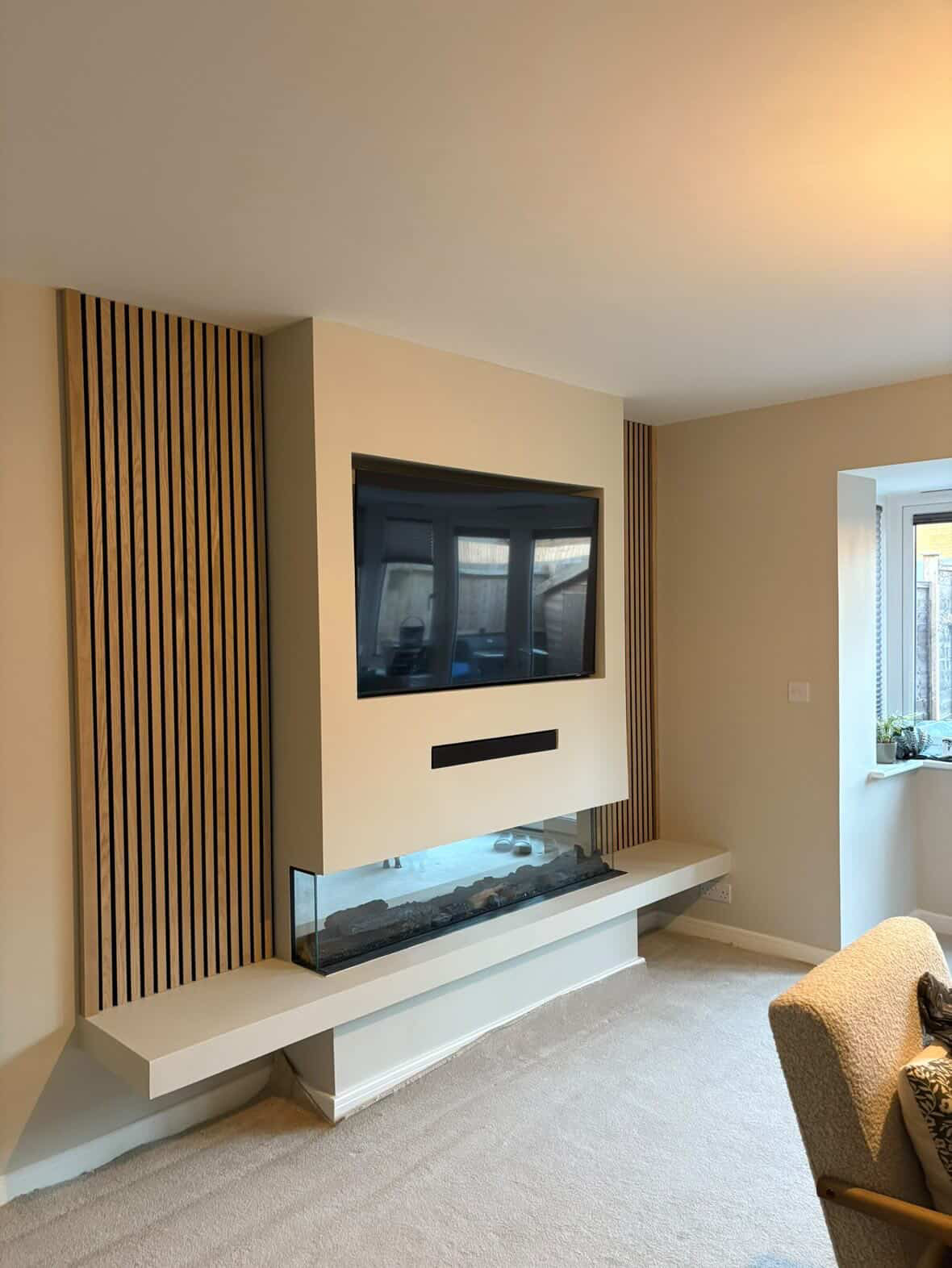 Daylight view of a media wall with oak slat panelling and floating shelf