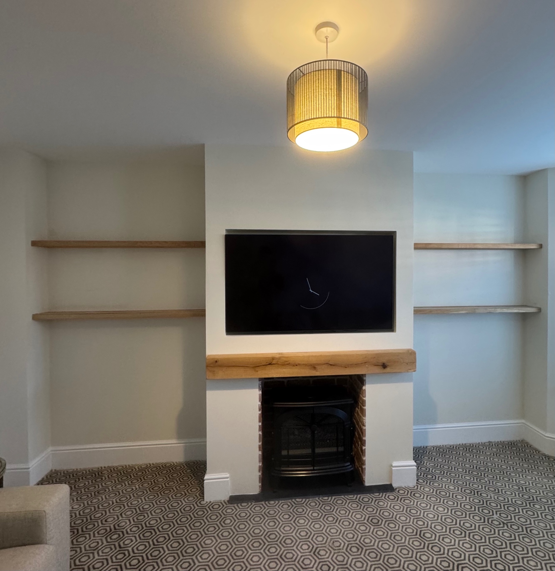 Chimney breast media wall with inset TV, oak mantel beam and floating alcove shelves